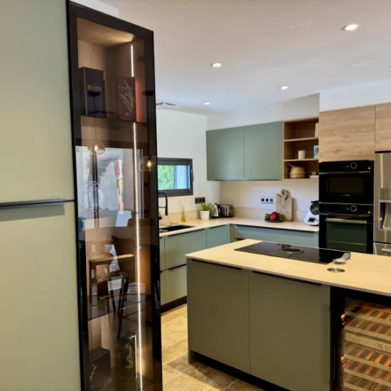 Aménagement d'une cuisine avec son bar avec des couleurs tendances comme le vert sauge, des matériaux nobles comme la pierre et le bois pour réchauffer l'ensemble.