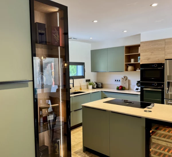 Aménagement d'une cuisine avec son bar avec des couleurs tendances comme le vert sauge, des matériaux nobles comme la pierre et le bois pour réchauffer l'ensemble.