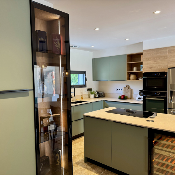 Aménagement d'une cuisine avec son bar avec des couleurs tendances comme le vert sauge, des matériaux nobles comme la pierre et le bois pour réchauffer l'ensemble.