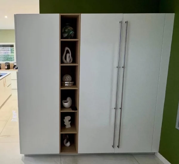 Aménagement d'une cuisine équipée laqué mat blanche avec des touches de bois sur les meubles hauts et le plan snack.