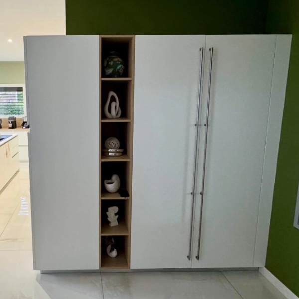 Aménagement d'une cuisine équipée laqué mat blanche avec des touches de bois sur les meubles hauts et le plan snack.