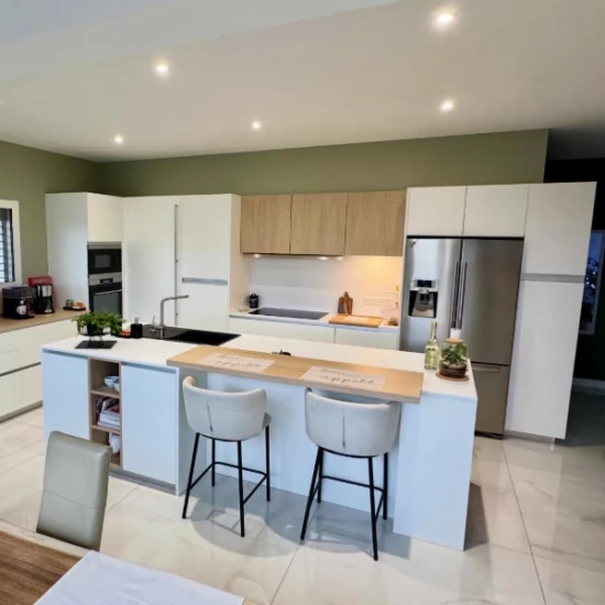 aménagement d'une cuisine laqué mat blanche avec des touches de bois sur les meubles hauts et le plan snack